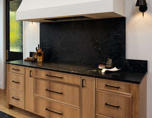 Kitchen with dramatic black splash and black countertop with custom Venetian plaster hood.