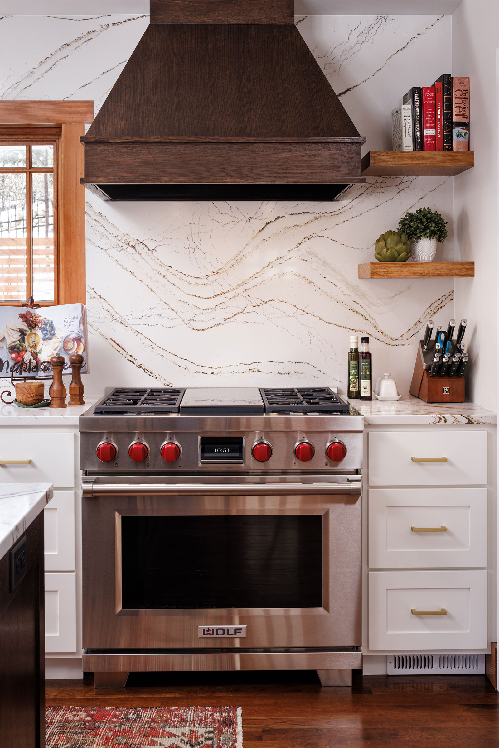 Kitchen remodel by Boyer Building Corporation in Minnetonka featuring a large gas range and hood with stone counter top and matching back splash