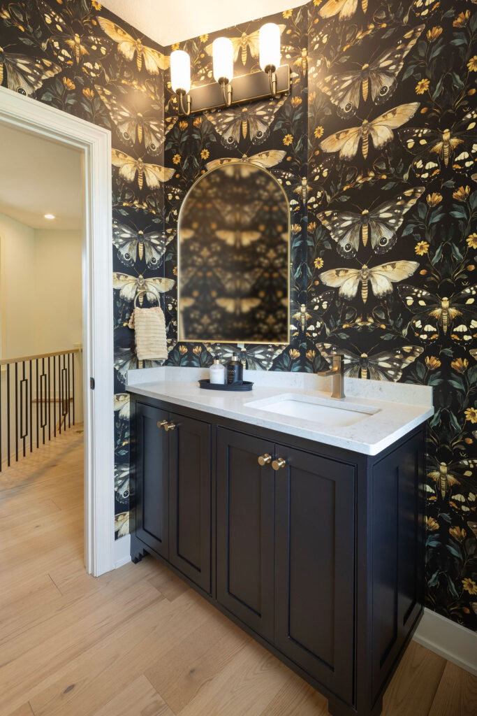 Stunning wallpapered powdered bathroom in blacks and butterfly wallpaper.