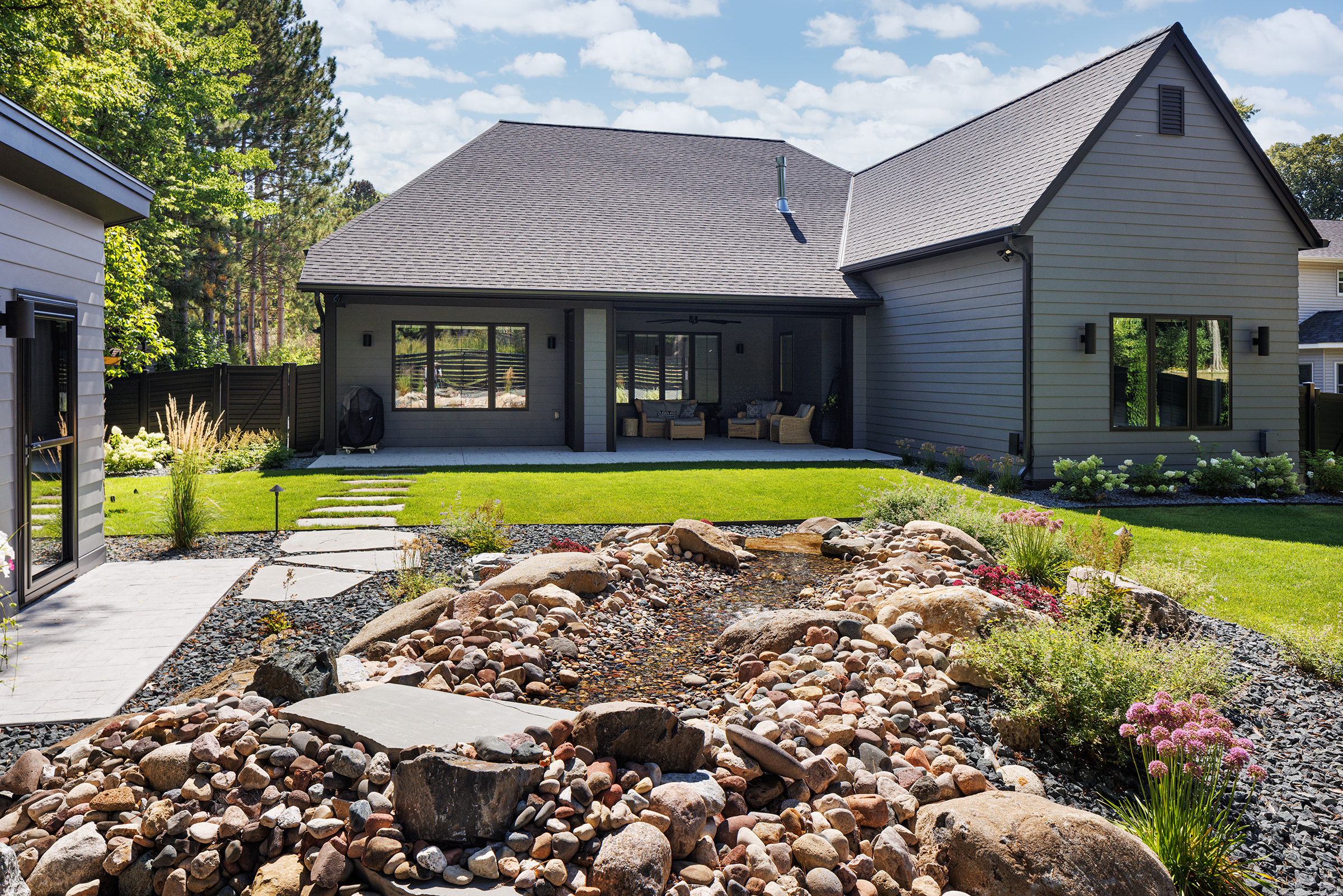 Exterior of Plymouth Custom Home showcasing dramatic dark exterior amongst gorgeous landscaped yard and she