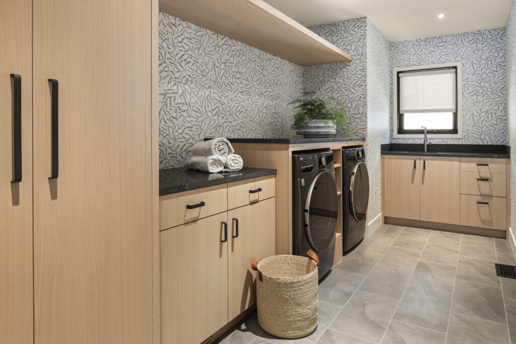 First floor remodeled laundry room with white oak cabinetry and wallpaper